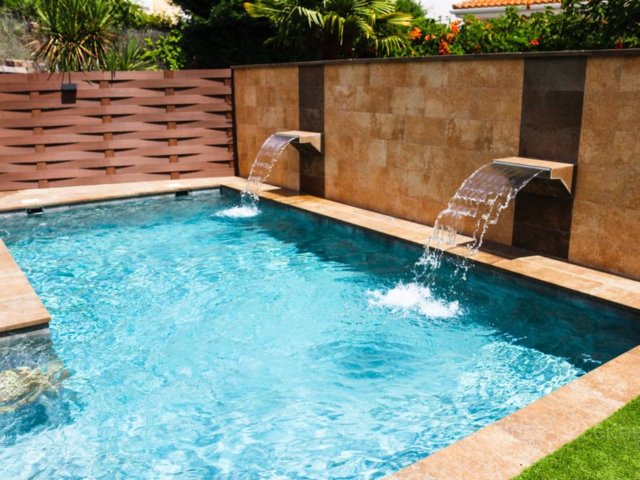 Dos cascadas saltan del muro para caer en la piscina