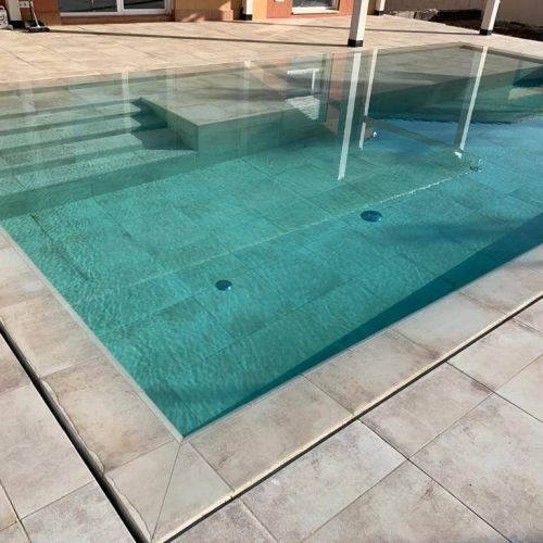 Color del agua turquesa con el porcelánico del interior de piscina igual al solado, desborde de la piscina por ranura invisible